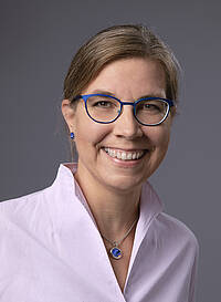 zu sehen ist das Portrait einer Frau in Bluse mit Brille, Katharina Zechner, Ihre Ansprechpartnerin an der vhs Weilheim für die Bereiche Gesundheit, Beruf und Führungen
