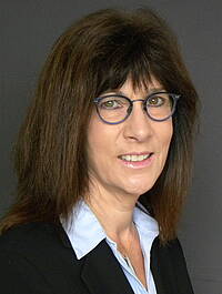 Zu sehen ist ein Portrait Susanne Börtzler, einer Frau mit Brille in Bluse und Blazer, tätig in der Verwaltung der vhs Weilheim